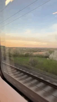 Blick aus dem Zugfenster auf vorbeiziehende Landschaft